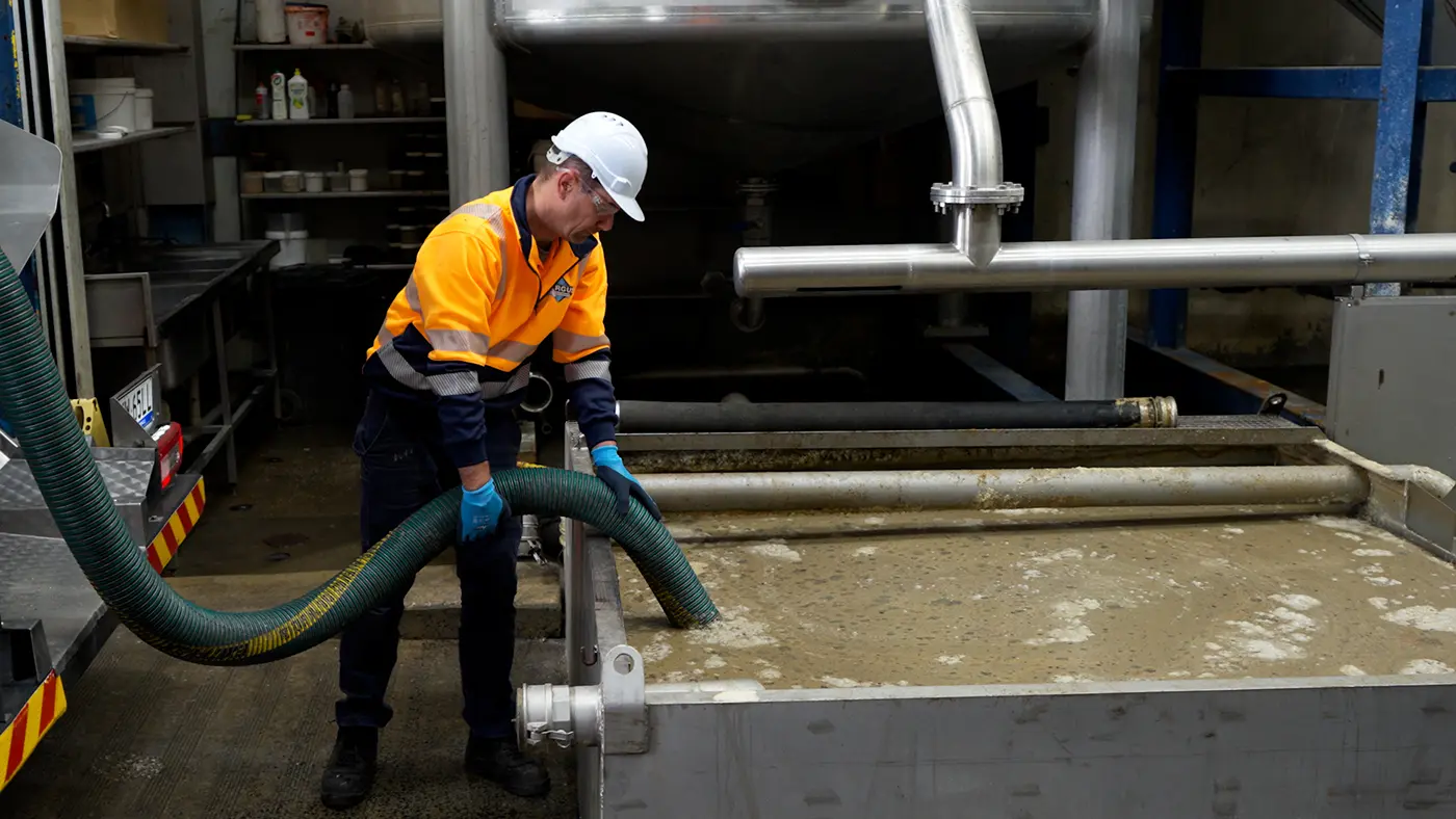 Vacuum hose being used to recover liquid and sludge around industrial process equipment