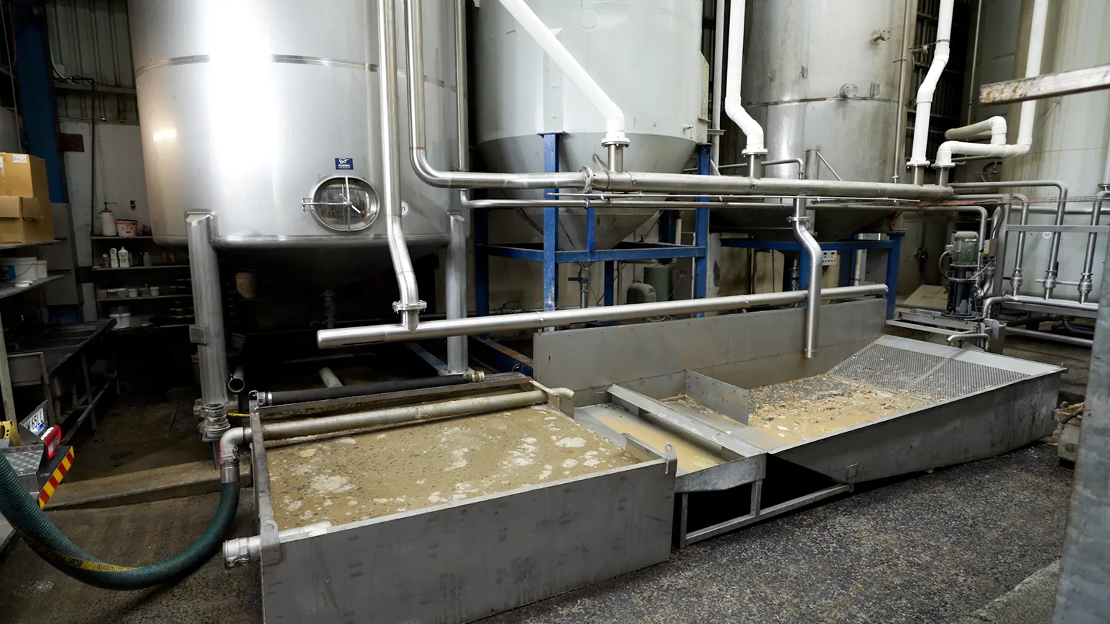 Industrial process area with stainless steel vessels, pipework and liquid collection troughs