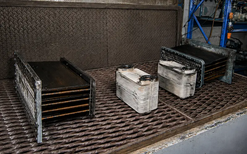 Heat exchanger and cooler components positioned inside an industrial cleaning bay for degreasing